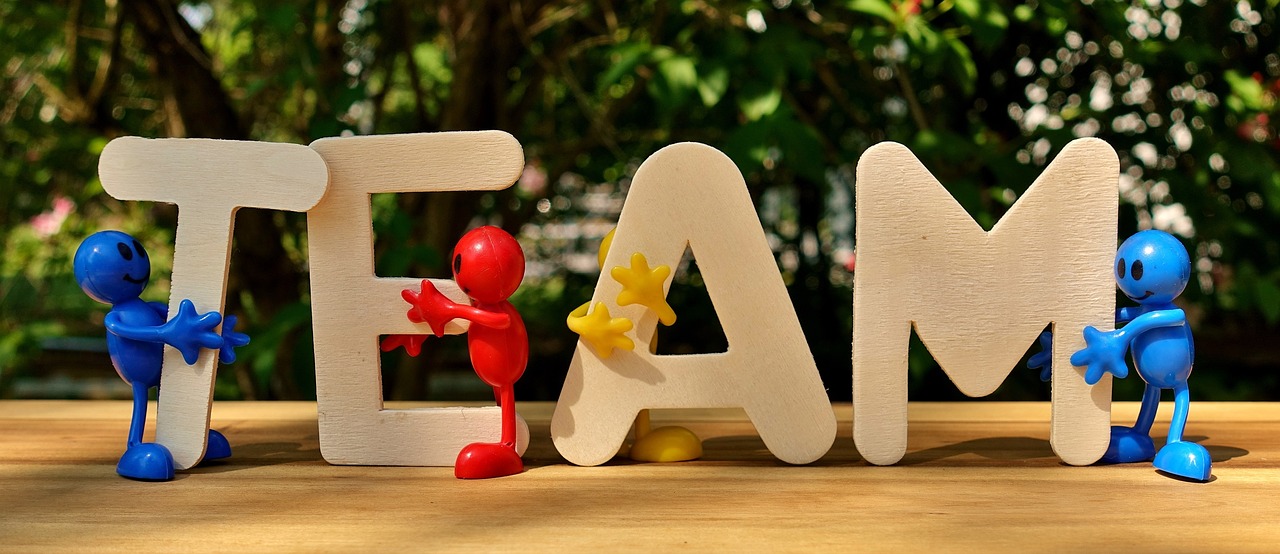 The word TEAM in wooden letters hugged by a few little people
